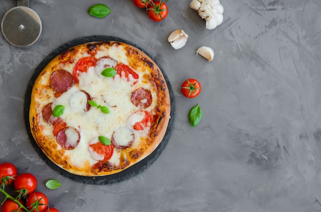 Pizza italiana casera con salsa de tomate, salami, queso y albahaca