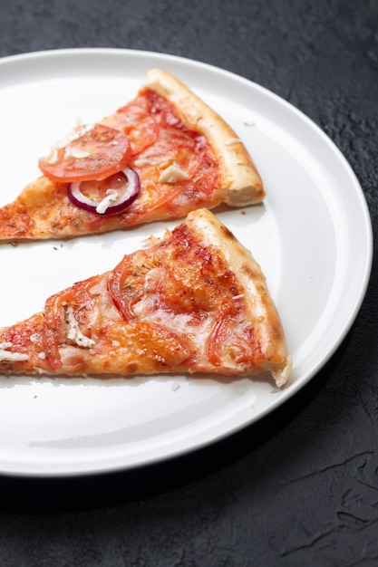 Pizza italiana clásica con tomates en una placa blanca.