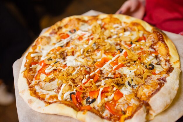 Pizza italiana com presunto, tomate, azeitonas, azeite, queijo parmesão e rúcula. Foto de estúdio de fundo colorido turva.