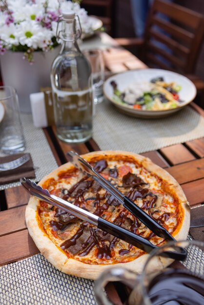 Pizza italiana com presunto, tomate, azeitonas, azeite, queijo parmesão e rúcula. foto de estúdio de fundo colorido turva.