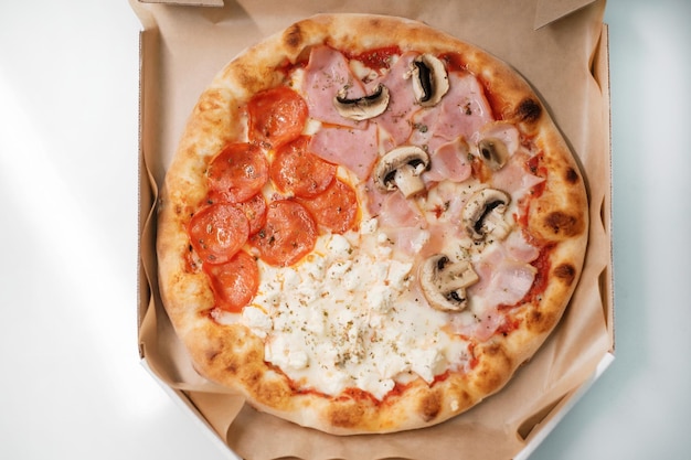 Pizza italiana com salame e cogumelos e presunto 4 estações em uma caixa de papelão o processo de fazer pizza conceito de culinária de comida de rua