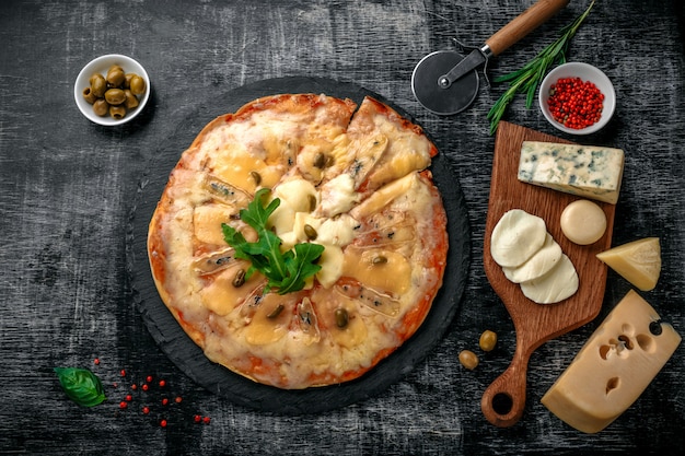 Pizza italiana com tipos diferentes de queijo em uma pedra e em uma placa de giz riscada preta. comida tradicional italiana