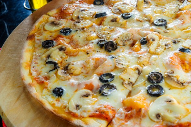 Pizza italiana com vários tipos de carnes e azeitonas pretas.