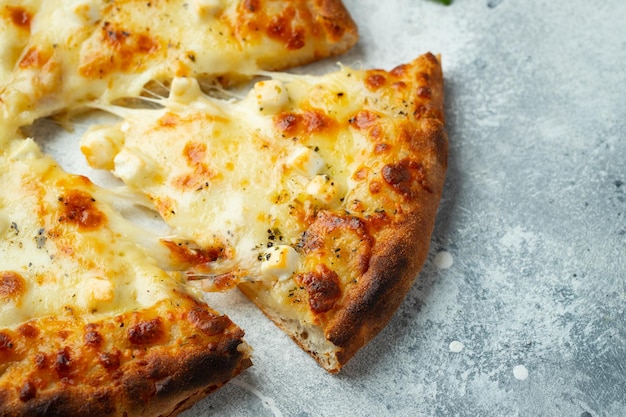 Pizza italiana cuatro quesos con queso estirado y albahaca sobre un fondo de hormigón ligero