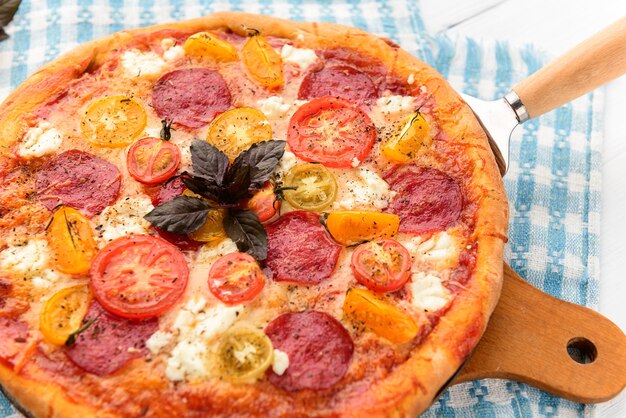 Pizza italiana de calabresa com salame e queijo em fundo branco de madeira rústica