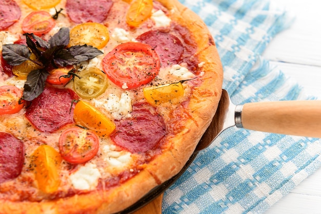 Pizza italiana de calabresa com salame e queijo em fundo branco de madeira rústica