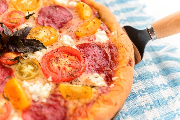 Pizza italiana de calabresa com salame e queijo em fundo branco de madeira rústica