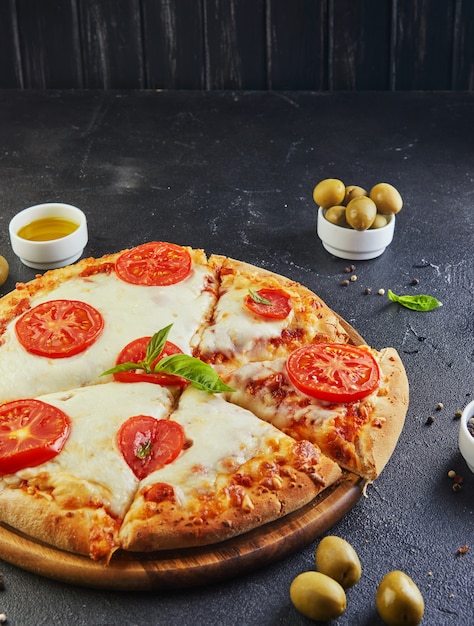 Pizza italiana e ingredientes para cocinar sobre un fondo de hormigón negro Vista lateral