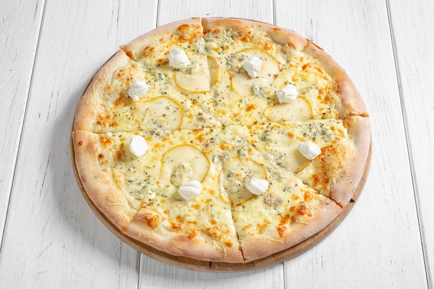 Pizza italiana fresca con diferentes tipos de queso y rodajas de pera en mesa de madera