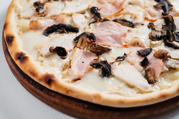 Pizza italiana con jamón, pollo y champiñones, primer plano