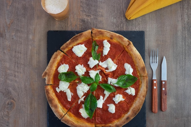 Pizza italiana Margherita con queso mozzarella de tomate y búfala adornado con albahaca fresca sobre pizarra negra