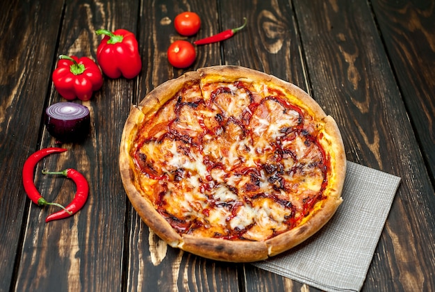 Pizza italiana en una mesa de madera con ingredientes, tomates, pimientos, cebollas