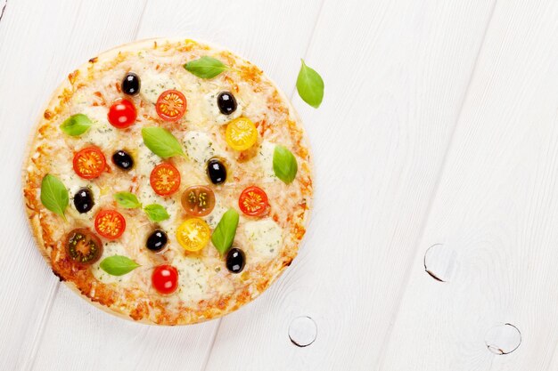 Pizza italiana con queso, tomates, aceitunas y albahaca