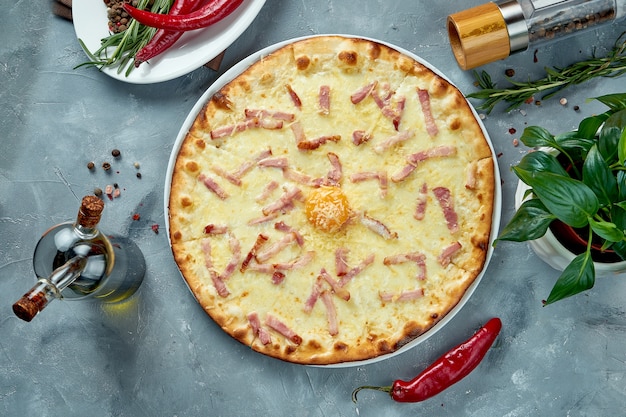 Pizza italiana con salsa carbonara, tocino, parmesano y yema. Vista superior, comida plana