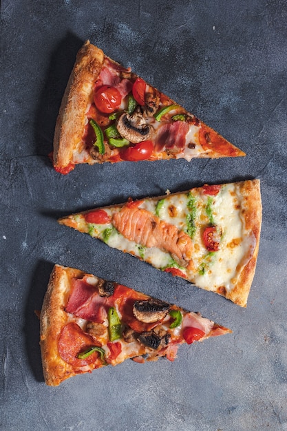 Pizza italiana con tomate, champiñones, tocino, salmón y pimiento. Entrega de comida sobre fondo negro