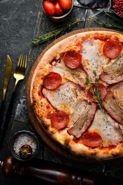 Foto pizza italiana tradicional com bacon e pepperoni entrega de comida em casa em um fundo de pedra preta