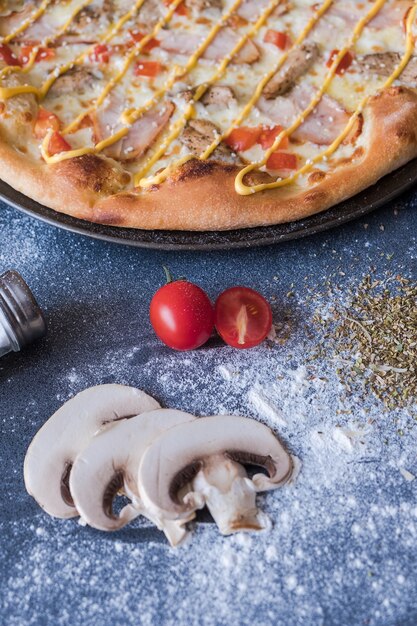 Pizza italiana tradicional con pollo, jamón en mesa de piedra azul oscuro