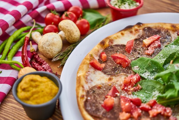 Pizza italiana con verduras y mostaza en la mesa de madera