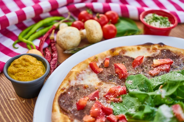 Pizza italiana con verduras y mostaza en la mesa de madera