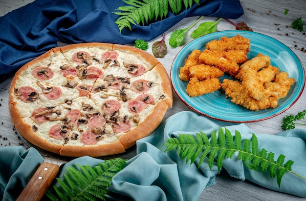 Pizza de jamón y champiñones en una espátula Palitos y nuggets de queso fritos y horneados Recién horneados con salsa cremosa de parmesano