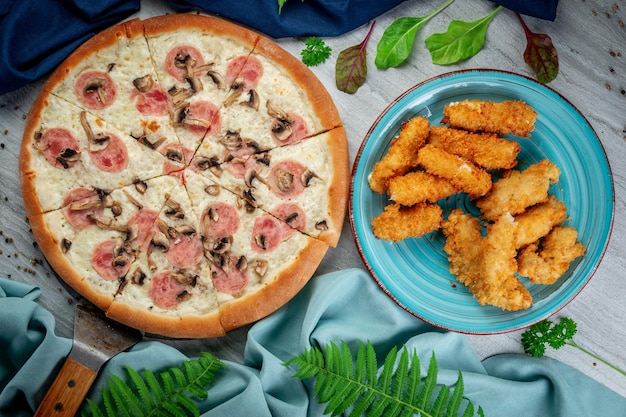 Pizza de jamón y champiñones en una espátula Palitos y nuggets de queso fritos y horneados Recién horneados con salsa cremosa de parmesano