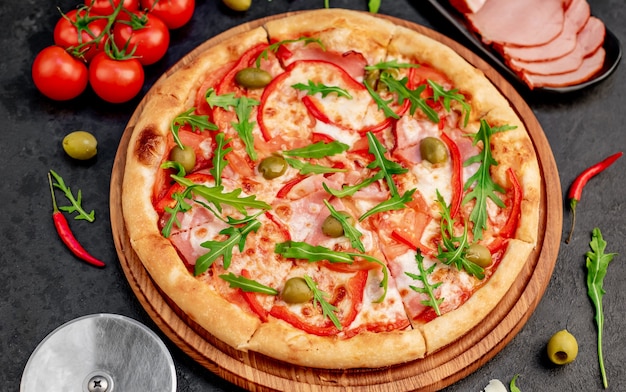 Pizza con jamón, tomates, queso sobre un fondo de piedra