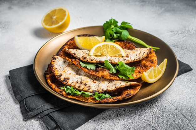 Pizza lahmacun turca con carne picada y tomates en un plato con perejil y limón Fondo blanco Vista superior