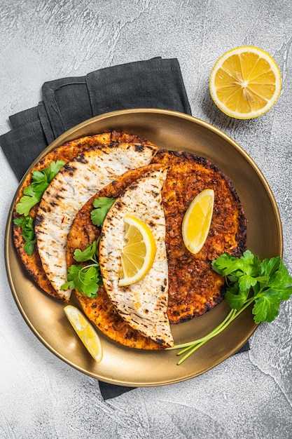 Pizza lahmacun turca con carne picada y tomates en un plato con perejil y limón Fondo blanco Vista superior