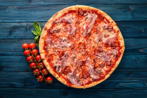 Pizza Lardon Bacon tomates cherry salchicha salami Sobre un fondo de madera Vista superior