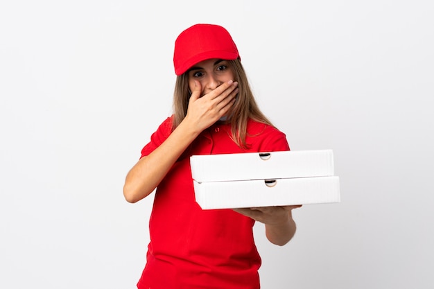 Pizza-Lieferfrau, die eine Pizza hält und vor dem Coronavirus mit einer Maske über isolierter weißer Wand mit Überraschung und schockiertem Gesichtsausdruck schützt