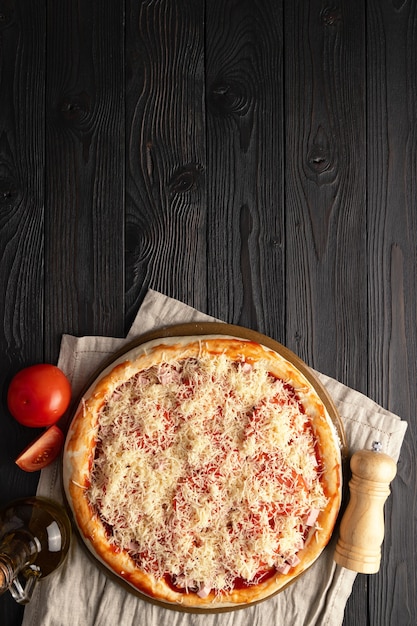 Pizza lista para el horno sobre un fondo de madera, lugar para el texto, vista superior.