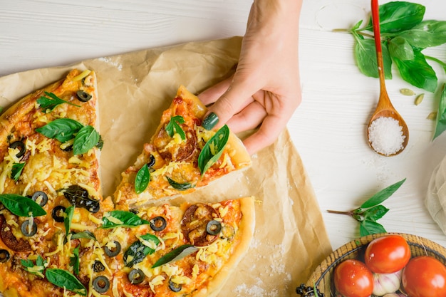 Pizza y mano de cerca sobre fondo blanco