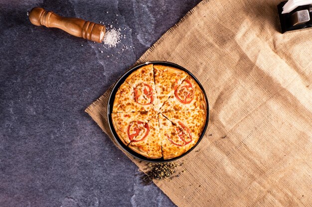 Foto pizza margarita italiana sobre fondo de mimbre y piedra con sal y especias