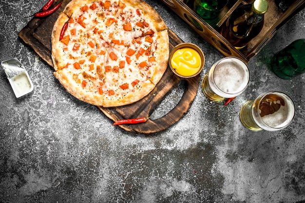 Pizza margarita con salsa y cerveza fresca.