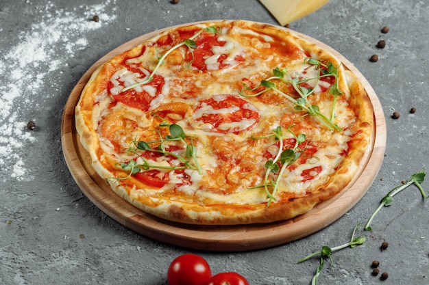 Pizza Margherita auf schwarzem Steinhintergrund, Draufsicht. Pizza Margarita mit Tomaten, Basilikum und Mozzarella-Käse hautnah