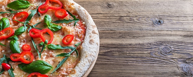 Foto pizza margherita con pimiento rojo y albahaca fresca sobre una mesa de madera