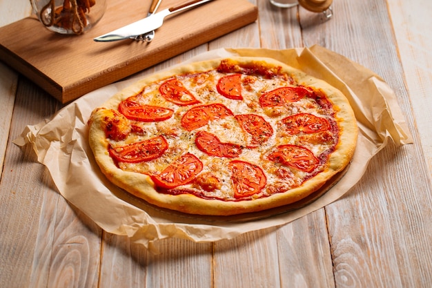 Pizza Margherita con tomates en el fondo de madera