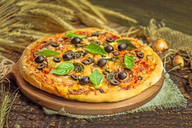 Pizza mista com frango, pimenta, azeitonas, cebola, manjericão na placa de pizza