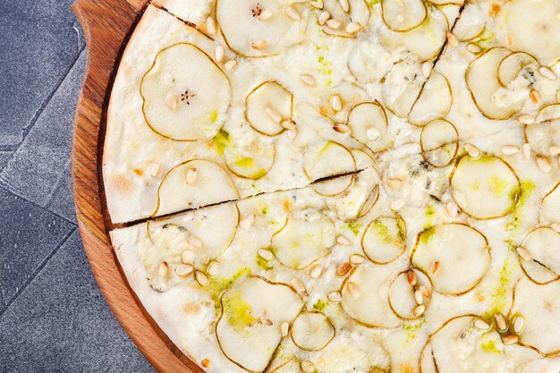 Pizza mit Birnen und Blauschimmelkäse auf einem Holzbrett. Nahansicht