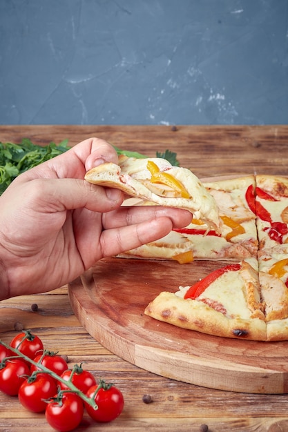 Pizza mit Fleisch, Gemüse und Pilzen, hölzerner Hintergrund