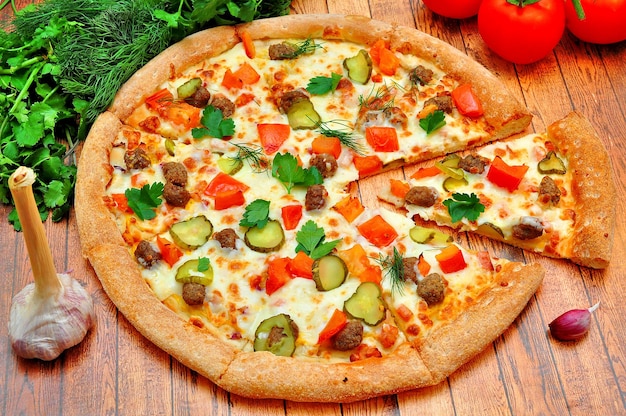 Pizza mit Fleisch, Gurken, Tomaten und Gemüse auf einem Holztisch