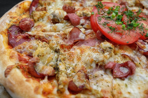 Foto pizza mit fleischwurst und hühnerkäse und tomaten auf grauem betonhintergrund mit selektivem fokus