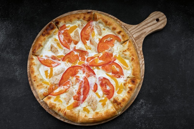 Pizza mit gemüsehuhn und käse auf einem holzbrett