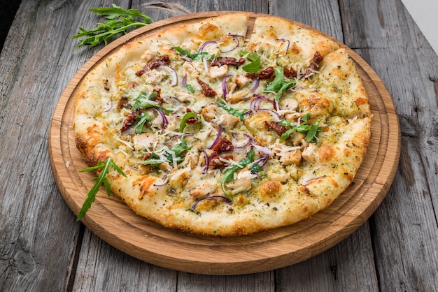 Pizza mit getrockneten Tomaten, Schinken, Rucola und Parmesan