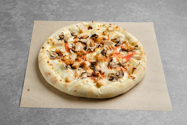 Pizza mit Hähnchenbrust und Champignons auf Pergamentpapier