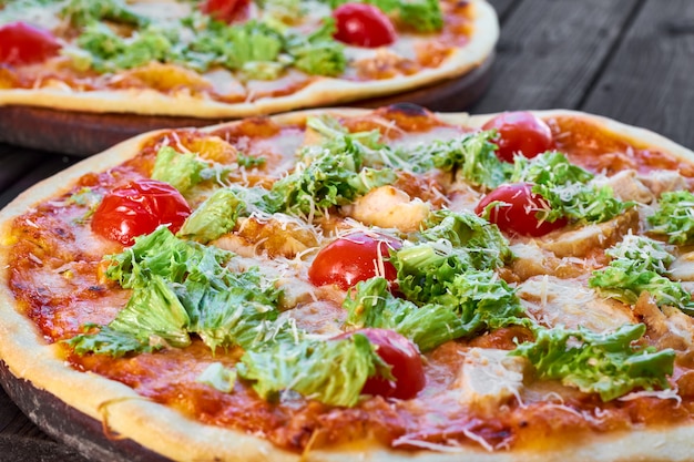 Pizza mit Huhn, Tomaten und Käse auf Holztisch