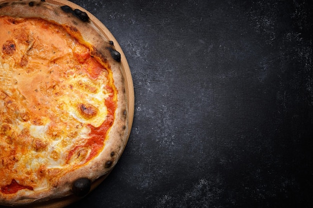 Pizza mit Käse und Tomaten auf dunklem Hintergrund