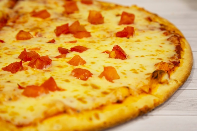 Pizza mit Käse und Tomaten, italienische Küche, auf hellem Holzhintergrund