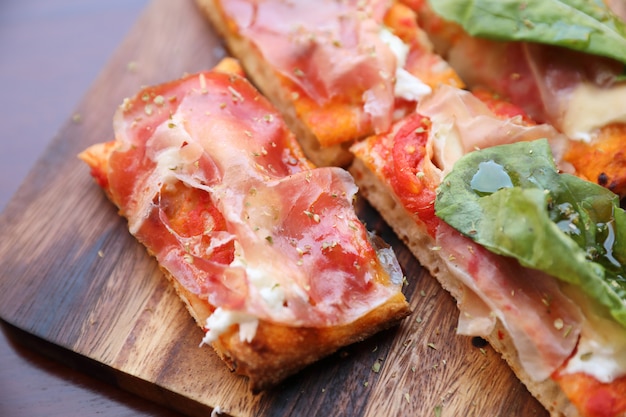 Pizza mit Parmaschinkensalatrakete und -parmesankäse auf dunklem hölzernem Hintergrundabschluß oben. italienisches Essen