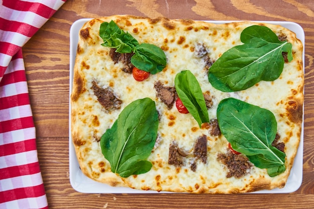 Pizza mit rotem Fleisch auf Holztisch